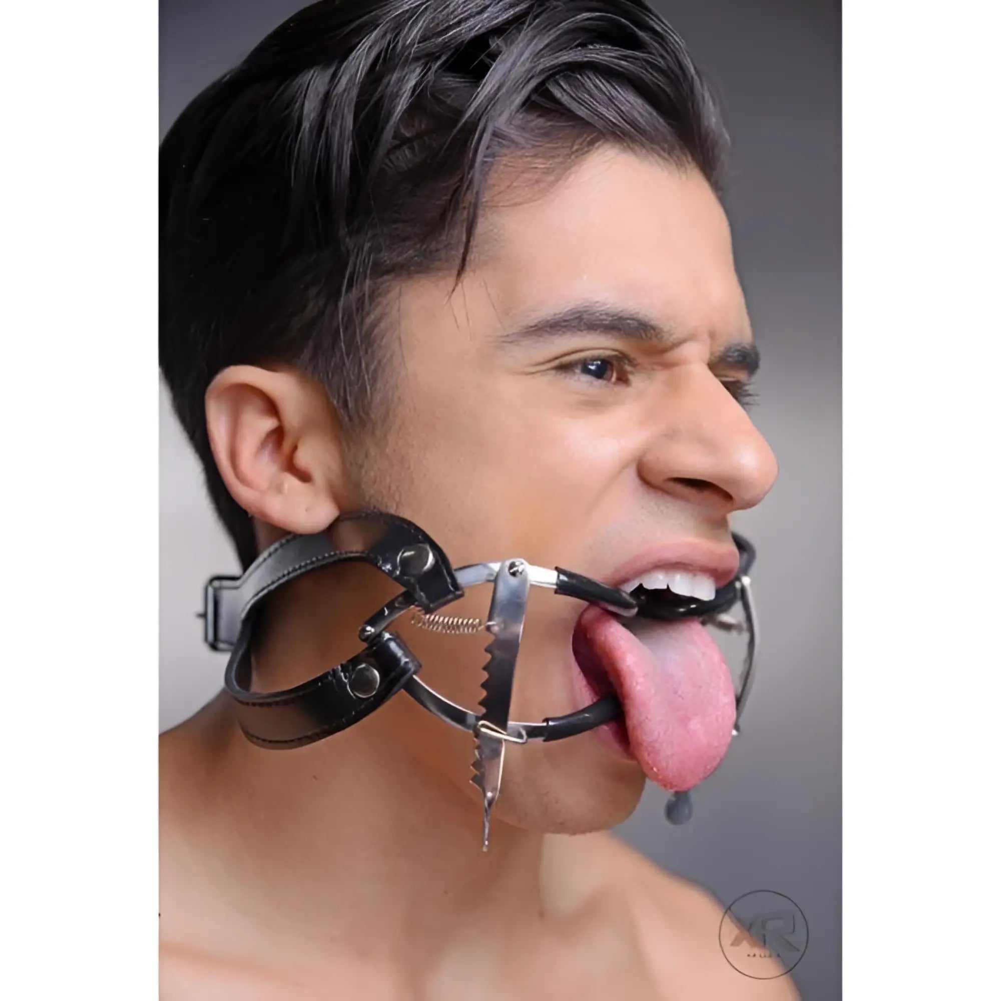 Master Series Ratchet Style Jennings Mouth Gag with black leather straps worn on a man’s face.