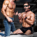 Master Series Scarlet Seduction set: Black leather cuffs with red trim, collar, blindfold, and ball gag on two men.