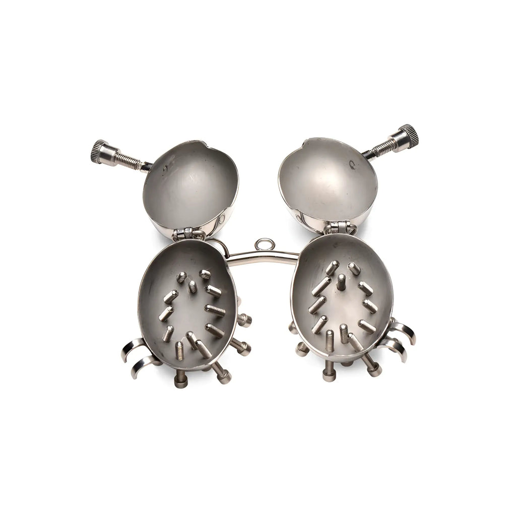 Master Series Scrotum Egg Shells with Spikes: hinged silver metal shells with internal spikes, open on a white ground.