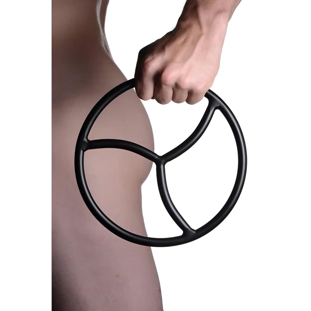 A hand holds a matte black Master Series Shibari suspension ring with a sleek, three-spoke internal design.