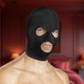 Black Master Series spandex hood with openings for eyes and mouth, worn by a shirtless man in a bedroom setting.