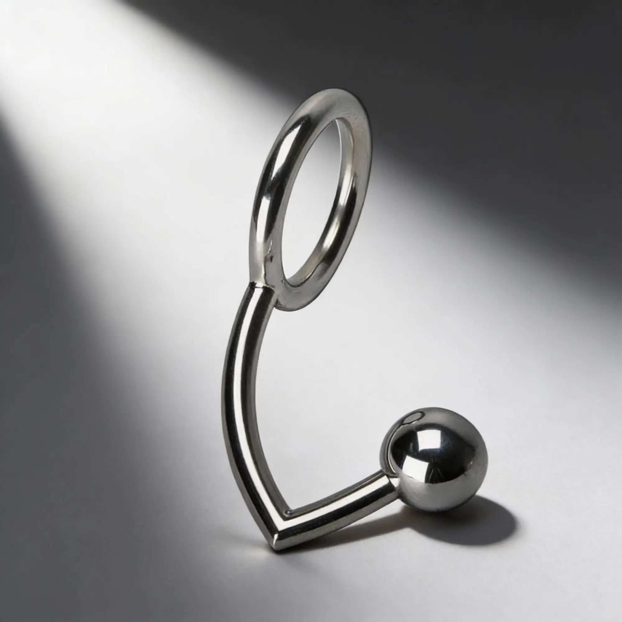 Master Series stainless steel anal intruder cock ring: a silver, L-shaped metal piece with a ring and a smooth ball tip.