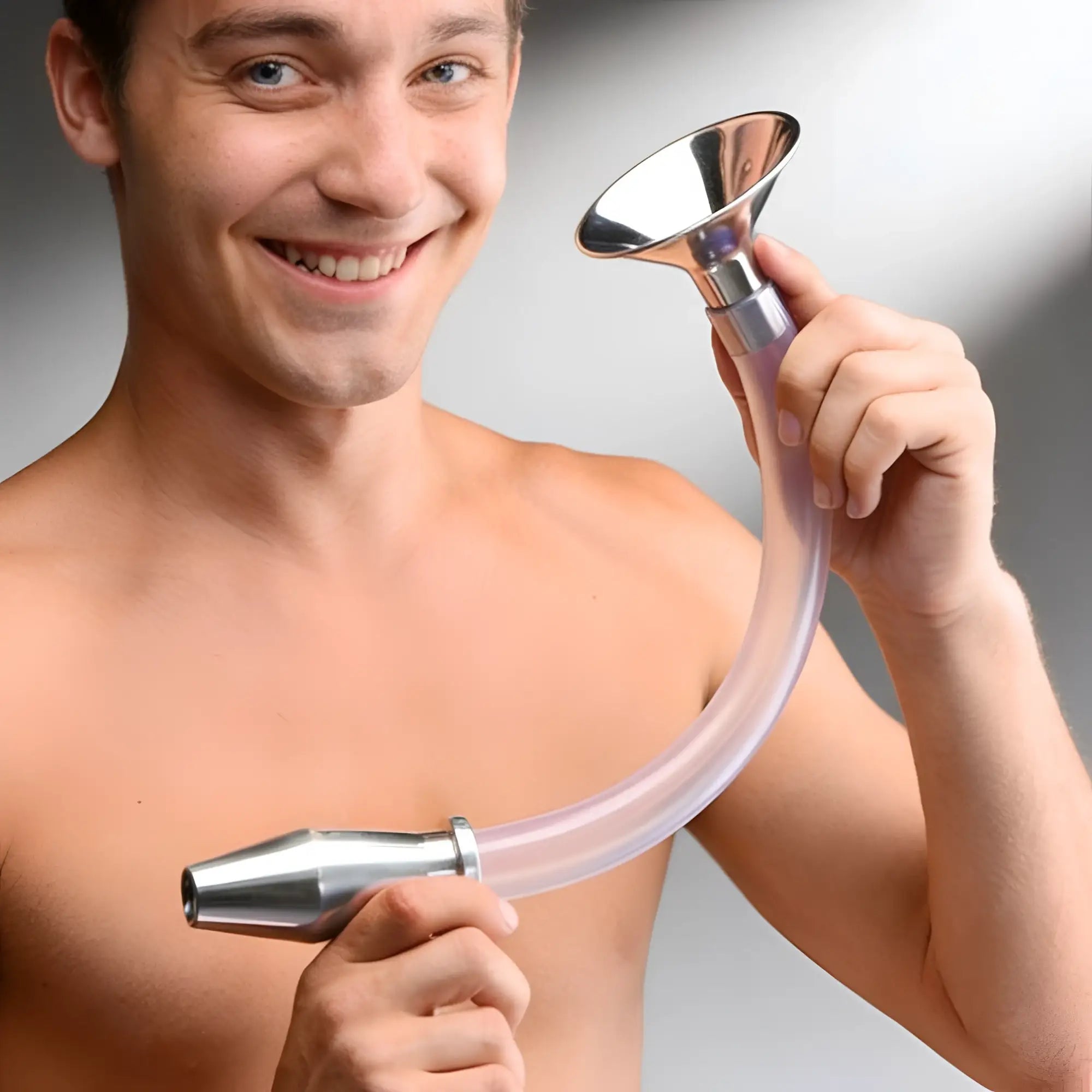 A smiling man holding a Master Series stainless steel funnel attached to a long, curved clear tube and hollow anal plug.