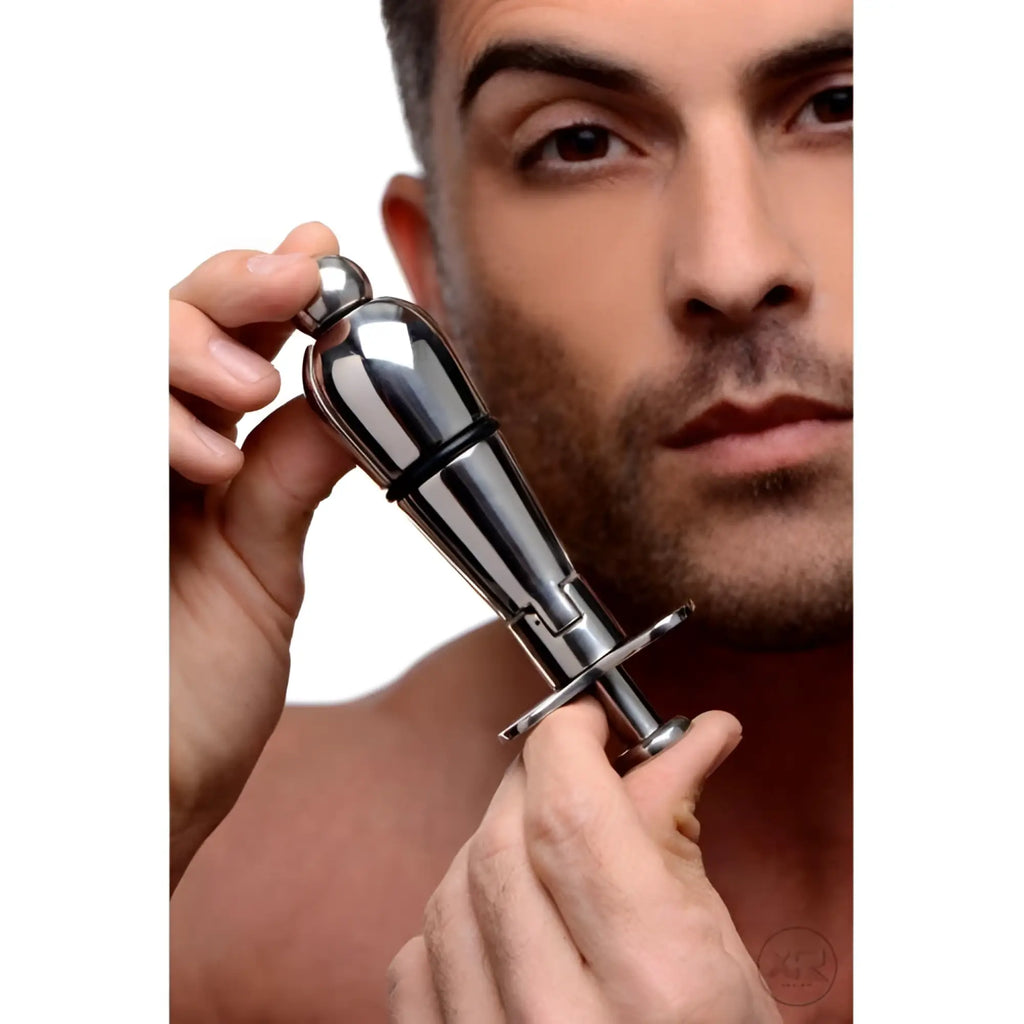 A man holding a polished silver Master Series Stainless Steel Locking Anal Plug with an adjustable mechanical design.