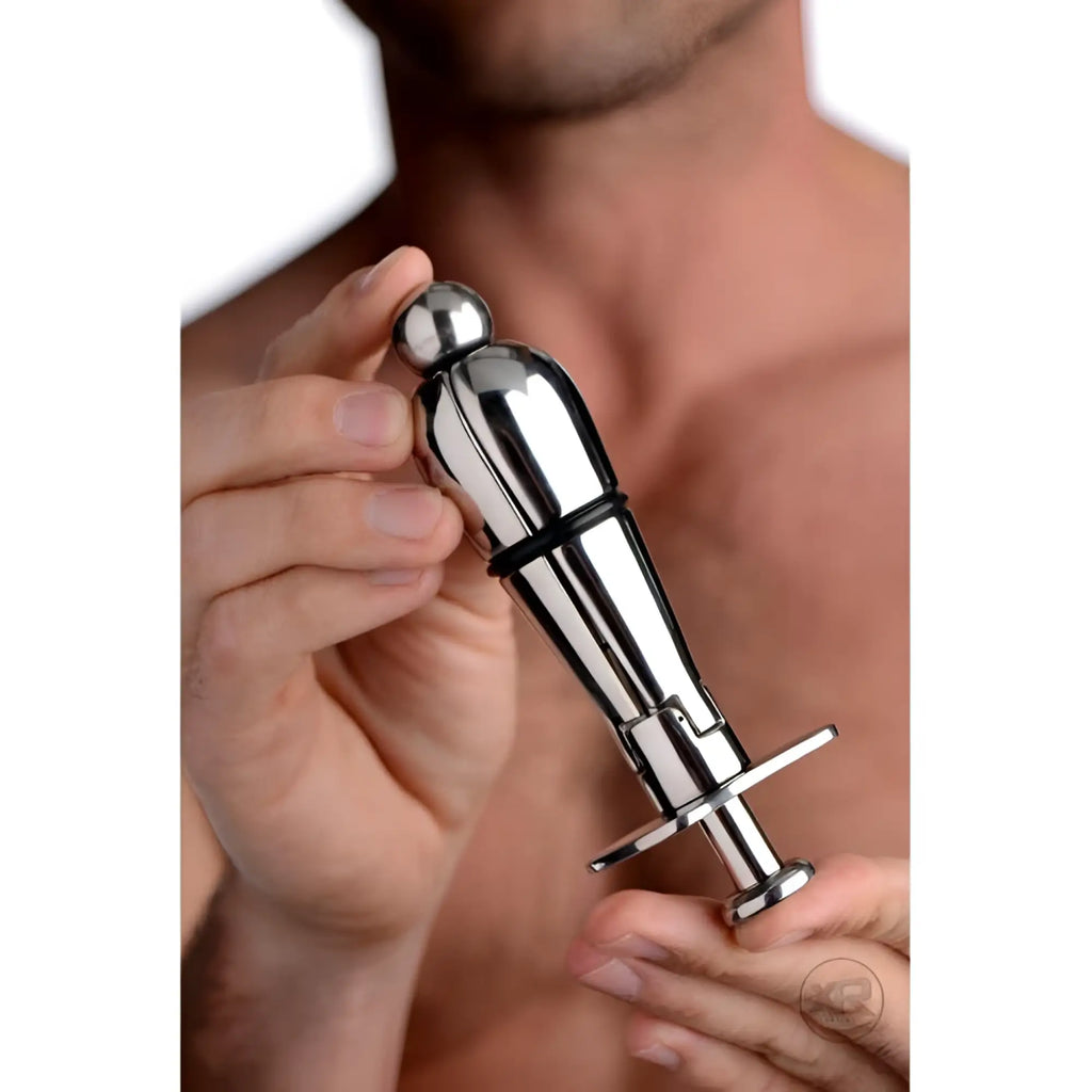A person holding a shiny, silver Master Series Stainless Steel Locking Anal Plug with a bulbous tip and base crossbar.