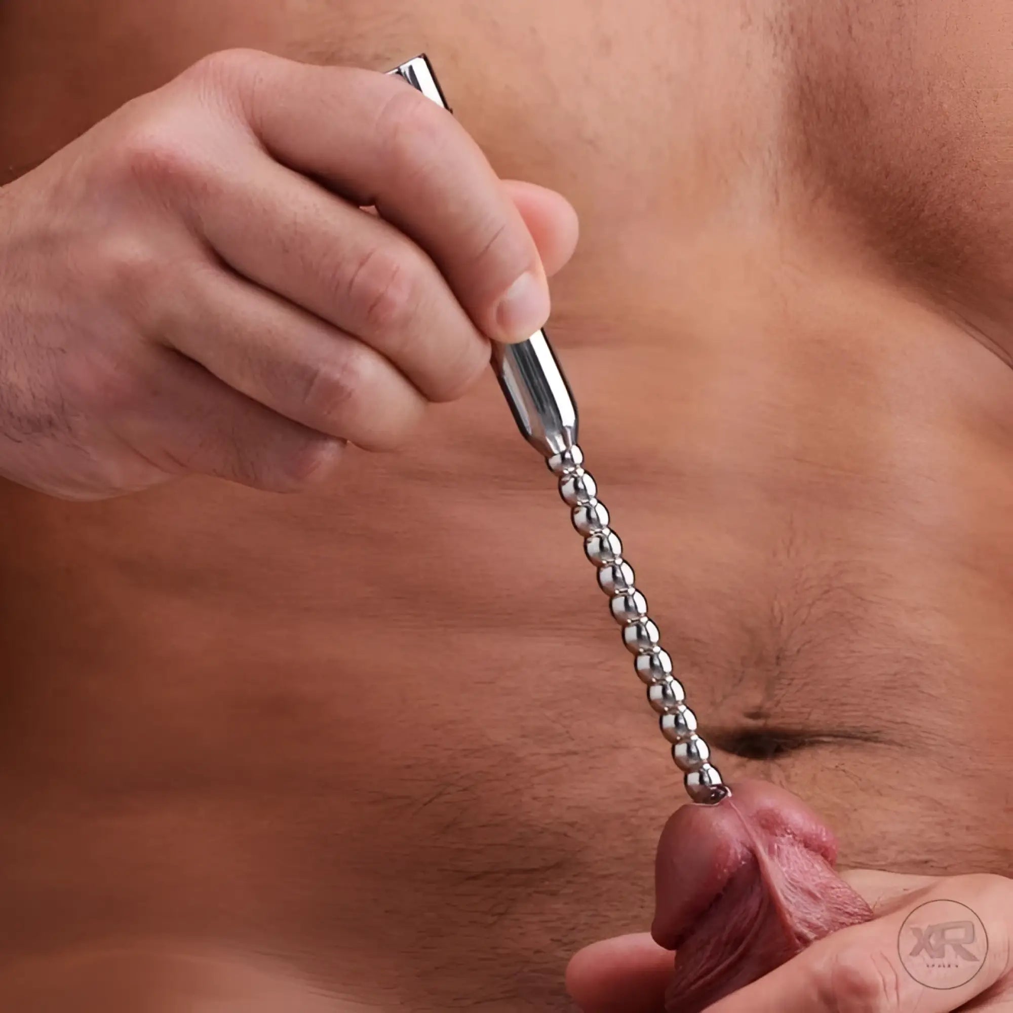 Master Series stainless steel beaded vibrating urethral sound being held against a penis.