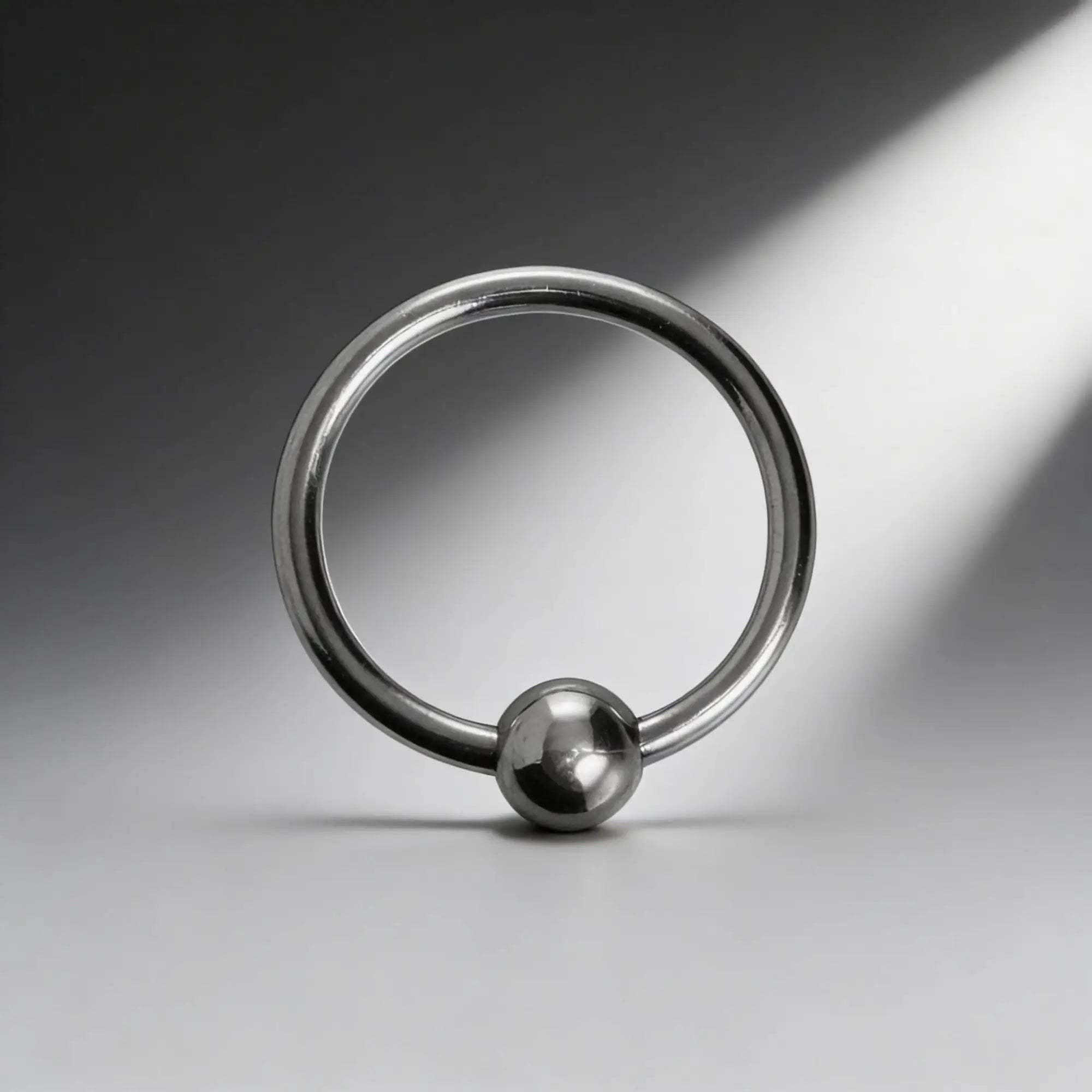Master Series Steel Ball Head Ring: A polished silver captive bead ring shown against a dramatic spotlight background.