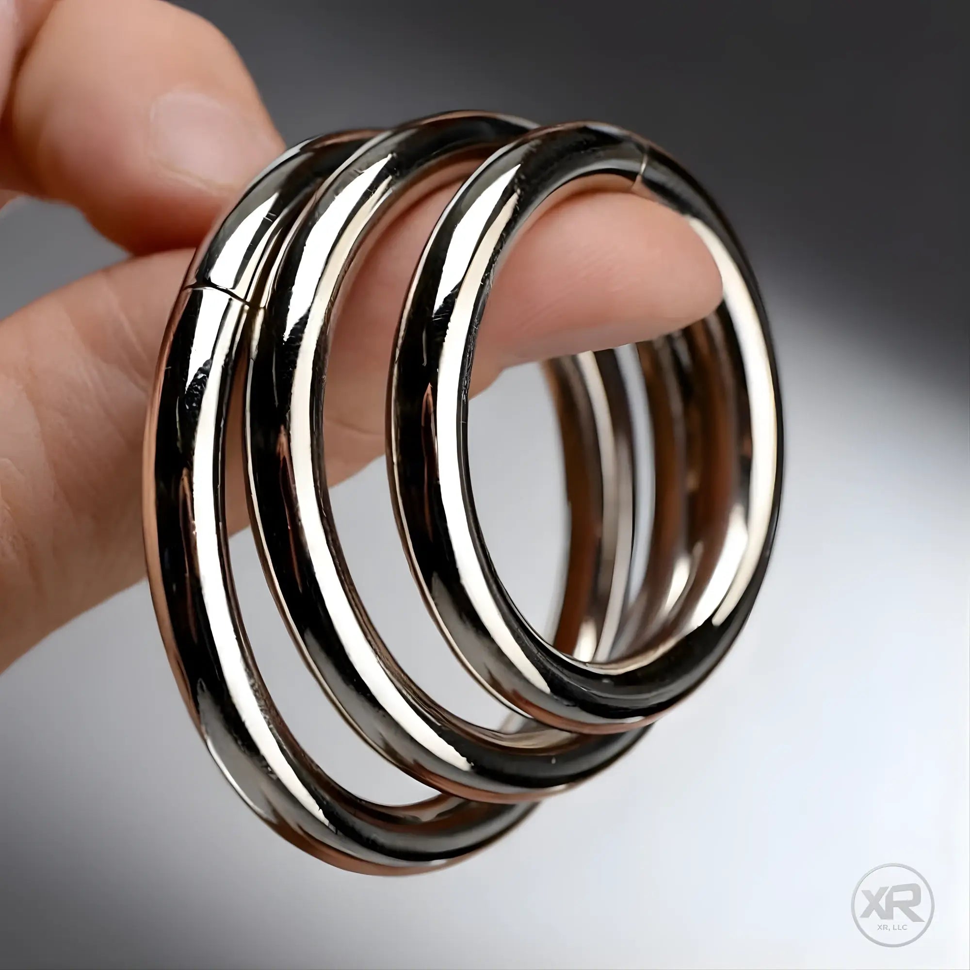 Master Series Steel Ring Set: A hand holds three smooth, polished silver-tone metal rings.