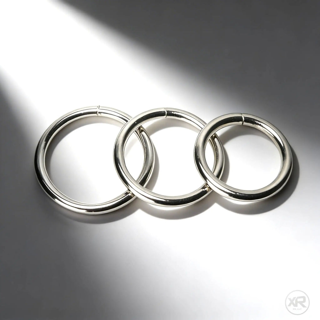 Master Series Steel Ring Set: Three polished, silver-toned circular metal rings resting on a smooth, shadowed surface.