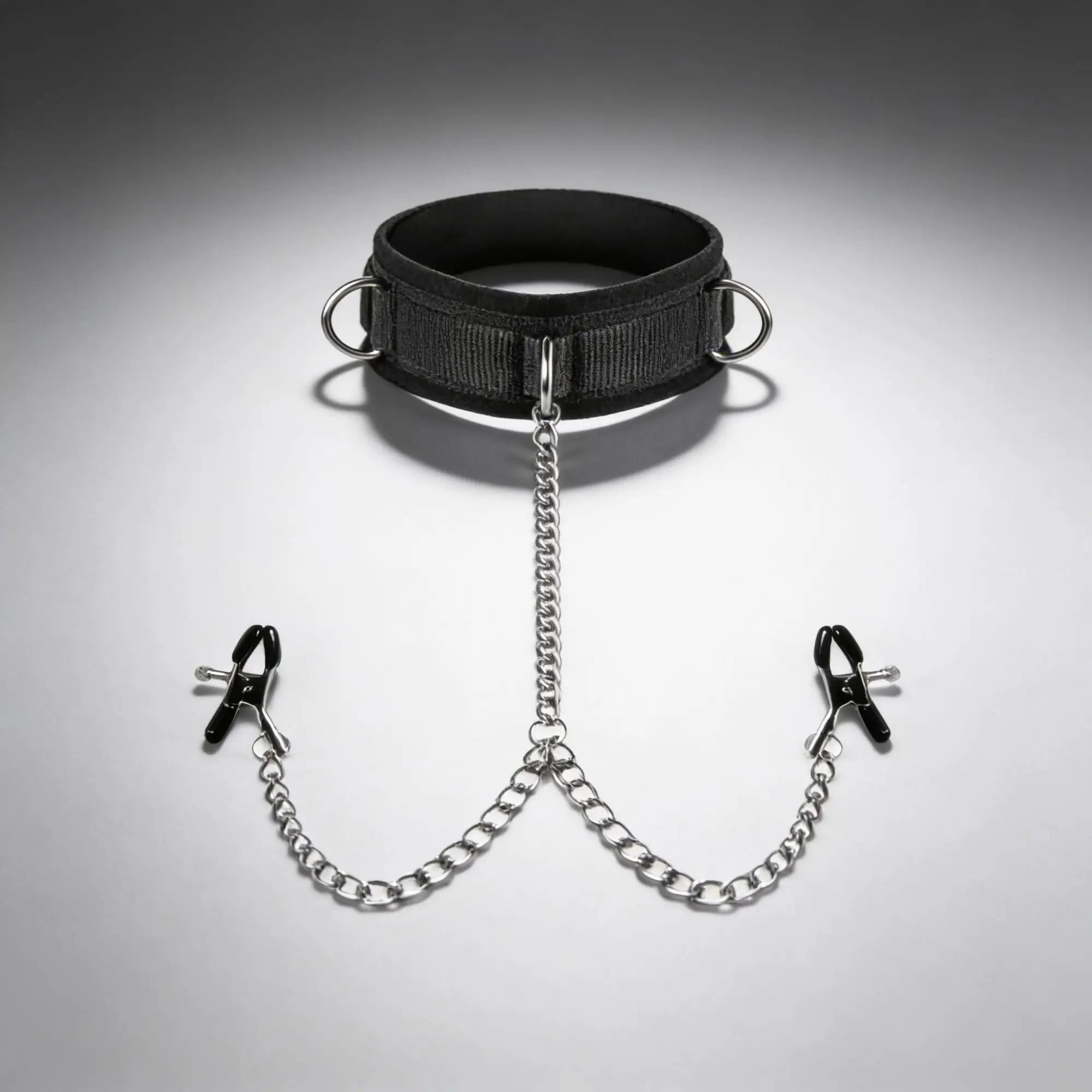 Master Series black collar with metal rings, attached via silver chains to two black-tipped nipple clamps.