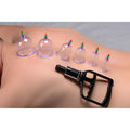 Master Series Sukshen 6-piece clear plastic cupping set with green and red valves on a person's back with a suction pump.