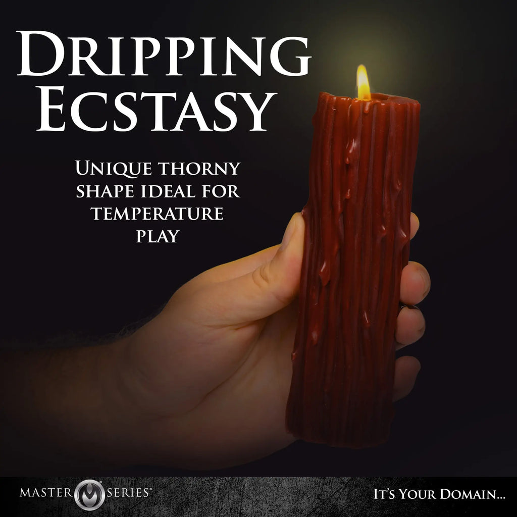 A hand holds a dark red Master Series Thorn Drip Candle with a textured, rugged surface and a glowing flame.