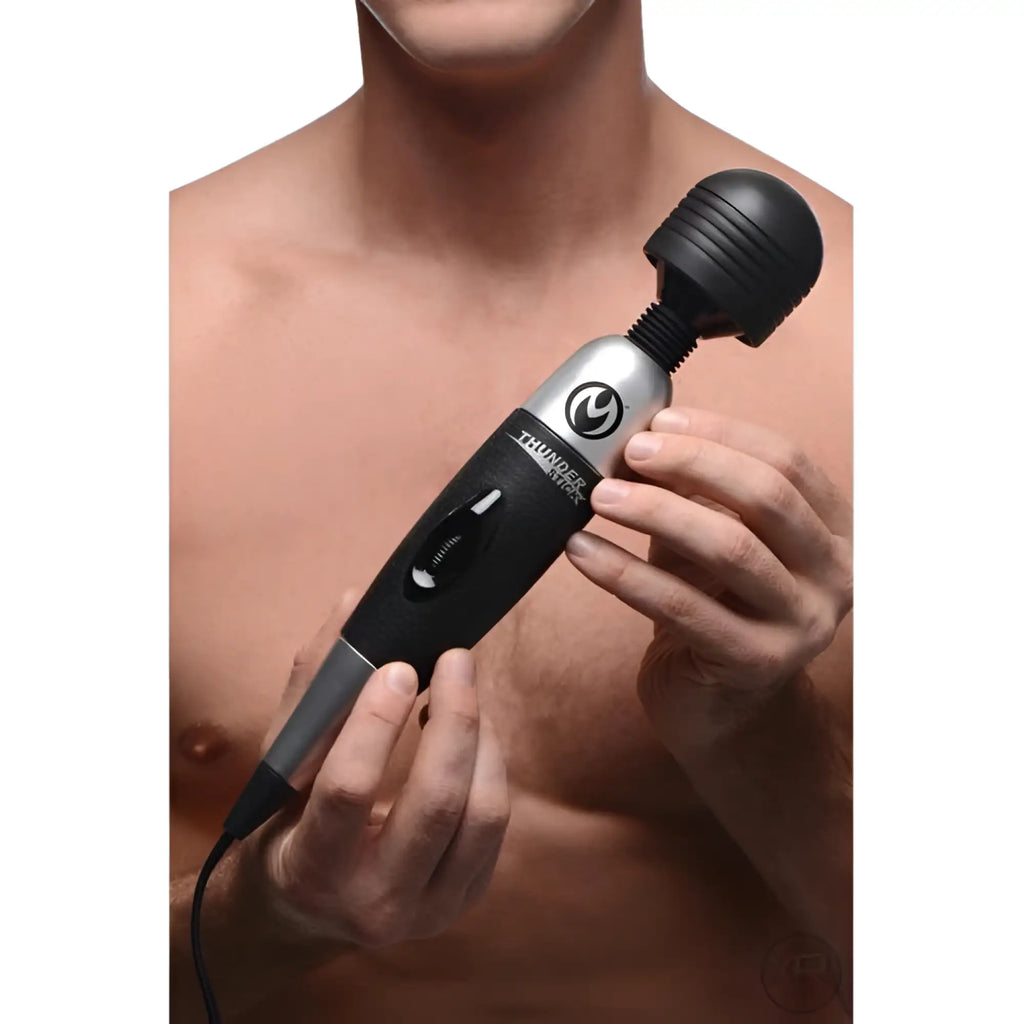A man holding a black and silver Master Series Thunderstick 2.0 power wand with a cord.