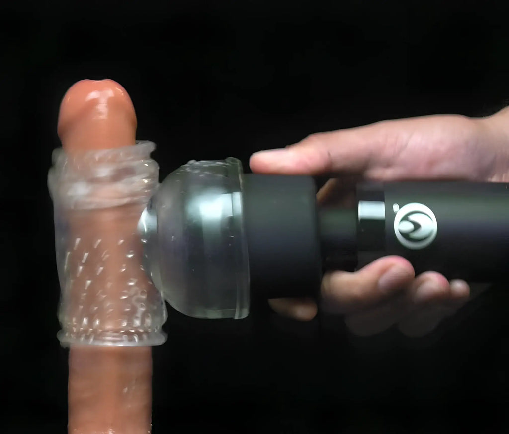 Master Series Thunderstick Pro wand massager in black, held against a textured clear attachment on a skin-toned toy.