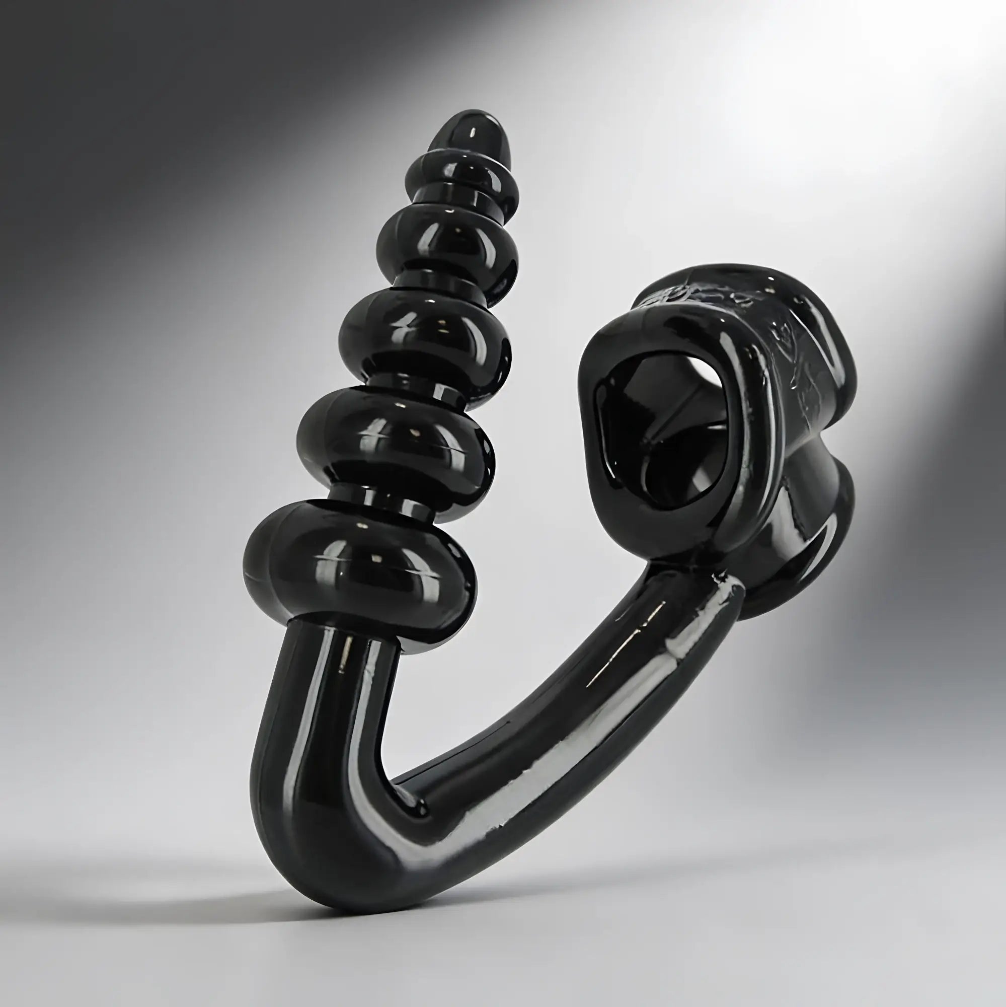 Master Series Tower Erection Enhancer: a glossy black, L-shaped toy with a ribbed post and a circular base loop.