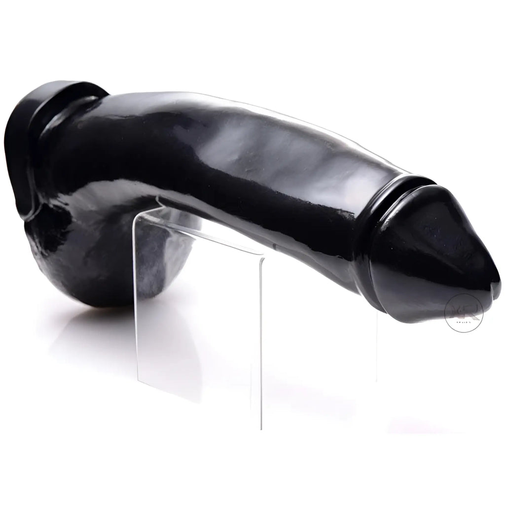 Master Series Tremendous Trevor: A realistic, glossy black dildo resting on a clear acrylic stand against white.