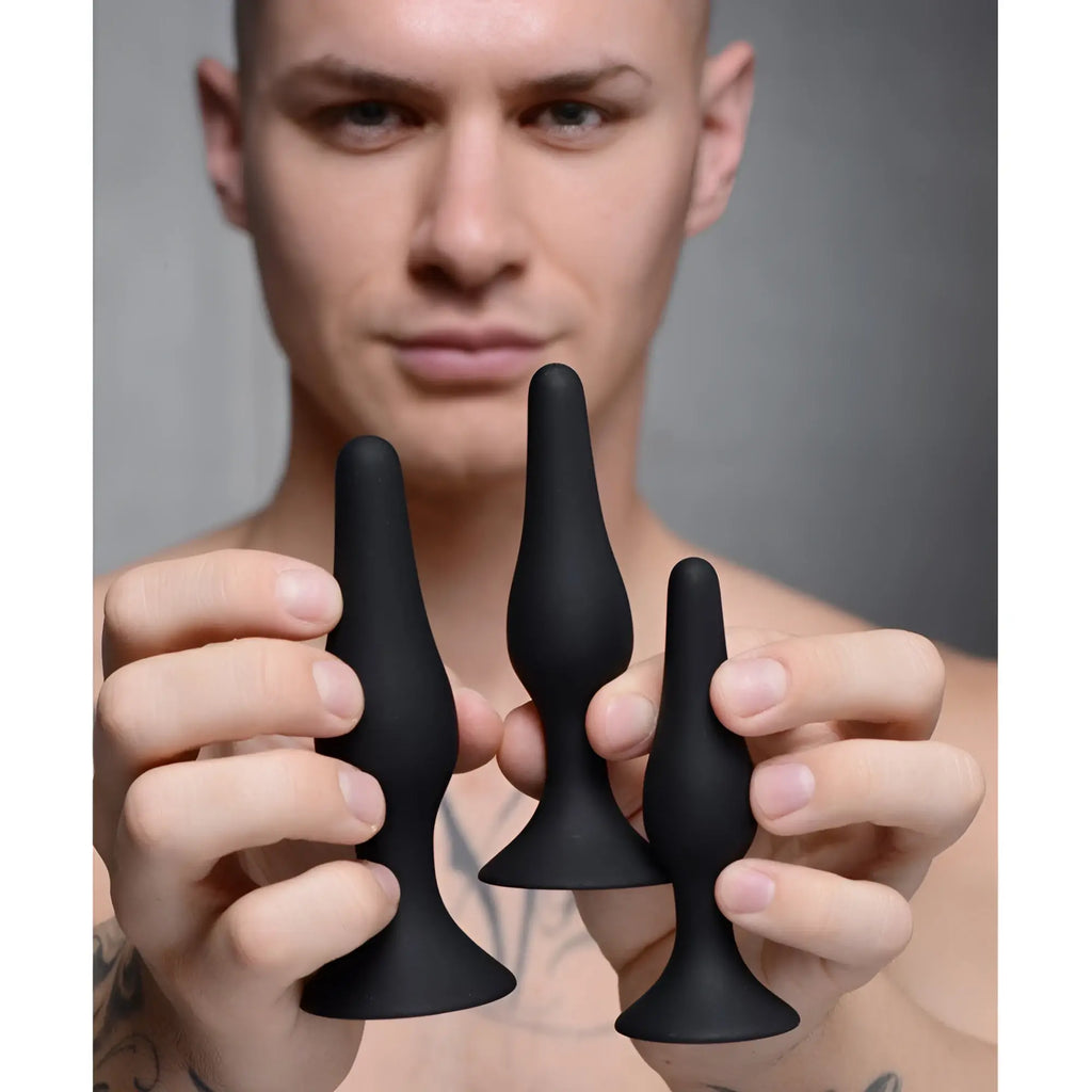 Master Series Triple Spire Tapered Silicone Anal Trainer set: three matte black, smooth, tapered plugs in varied sizes.