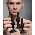 Master Series Triple Spire Tapered Silicone Anal Trainer set: three matte black, smooth, tapered plugs in varied sizes.
