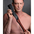 Master Series Wooden Slapper features a polished dark wood handle and a flexible, matte black strap held by metal studs.