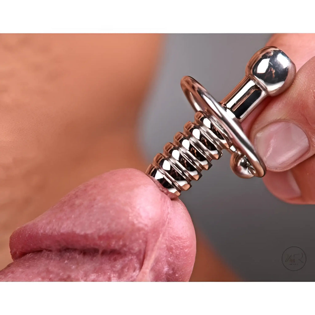 Master Series XL silver, ribbed urethral penis plug with hollow core being held against the tip of a penis.