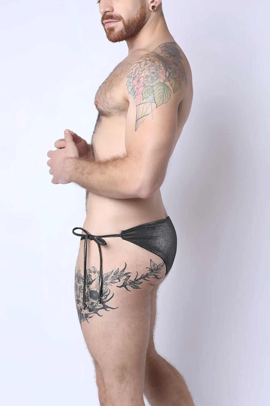 Black shiny metallic Mauii side tie reversible bikini swim trunks with tied waistband shown from the front