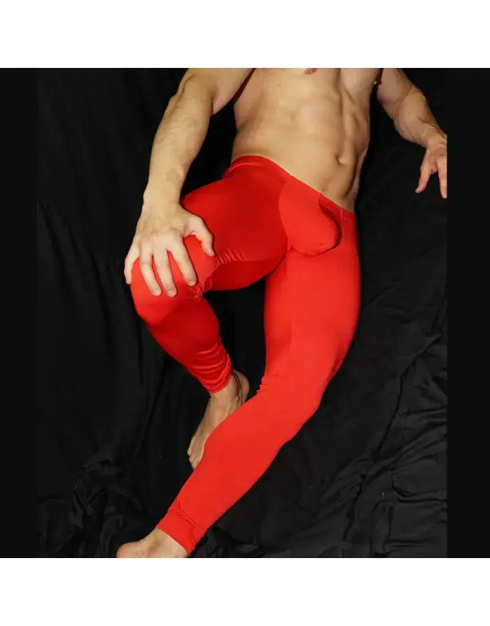 Red men's tights made of stretchy material featuring a bulge-enhancing design shown on a model by Arroyman.