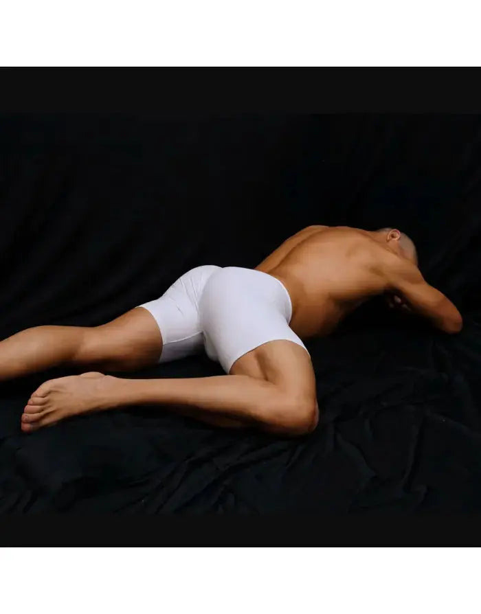 White compression shorts by Arroyman featuring a snug fit and smooth fabric shown on a model lying on a dark surface.