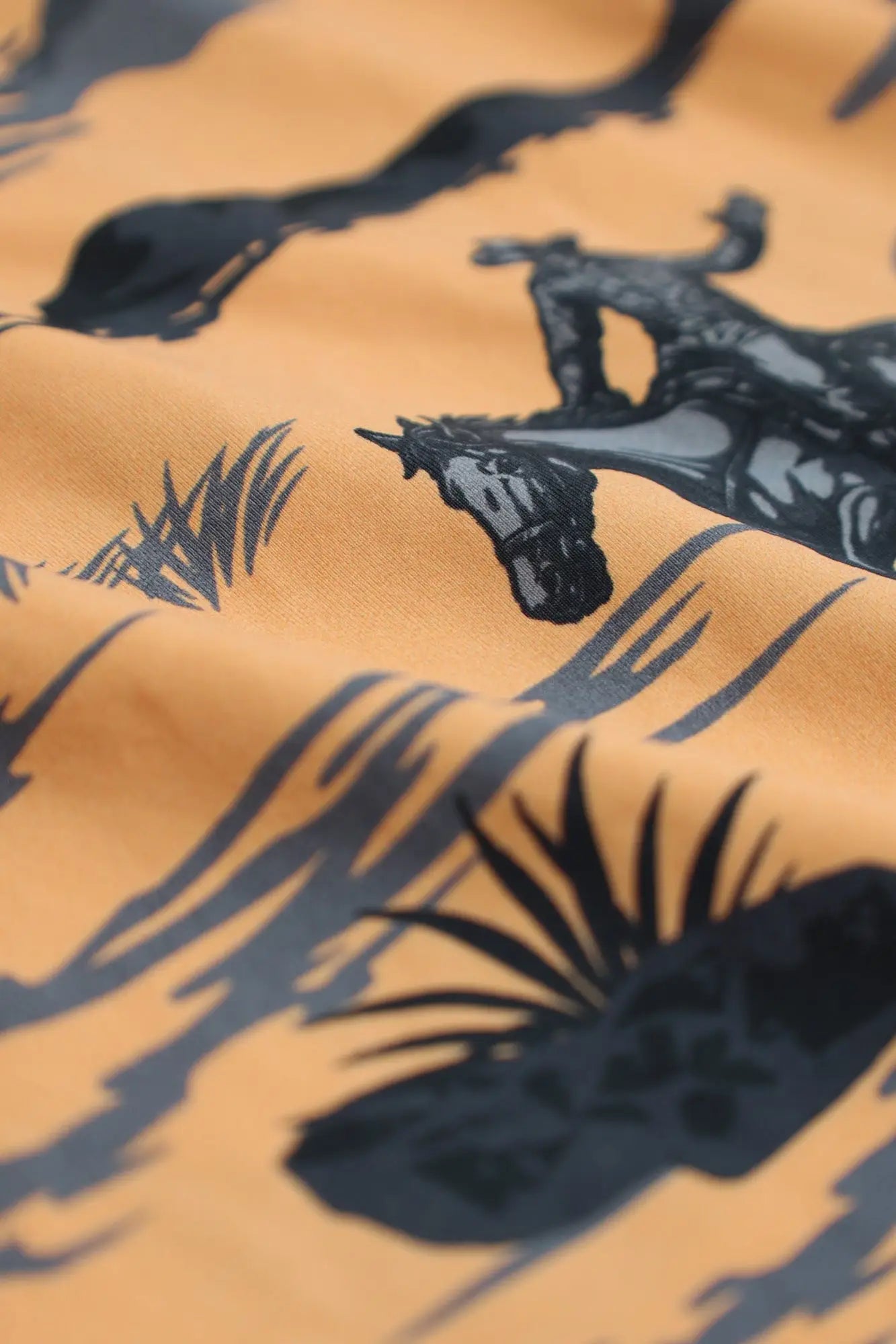 Men’s boxer briefs featuring orange fabric with black horse and palm frond silhouettes in a wild west tropical print