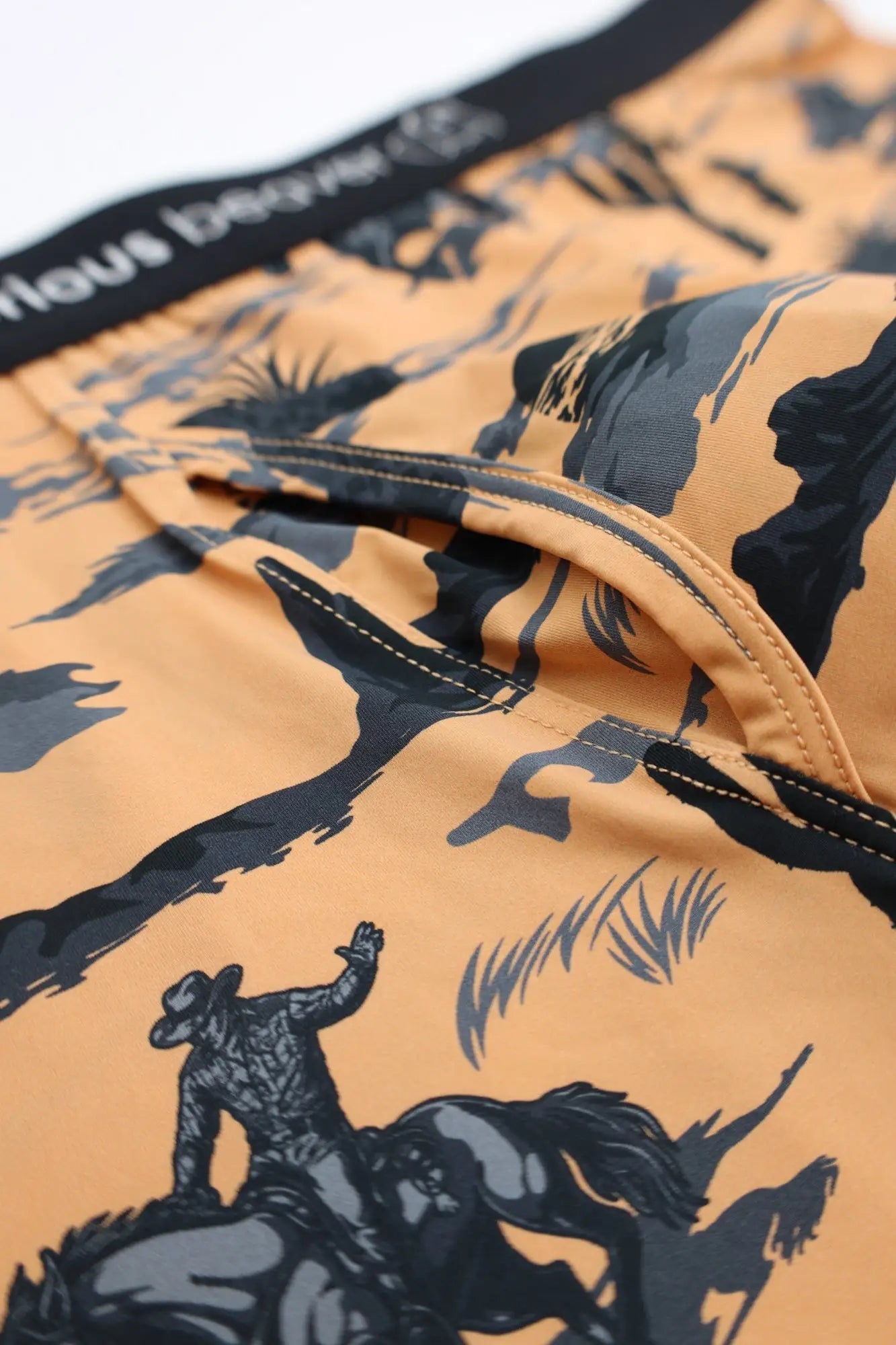 Men’s orange swim trunks with black and gray cowboy rodeo print from wild west collection