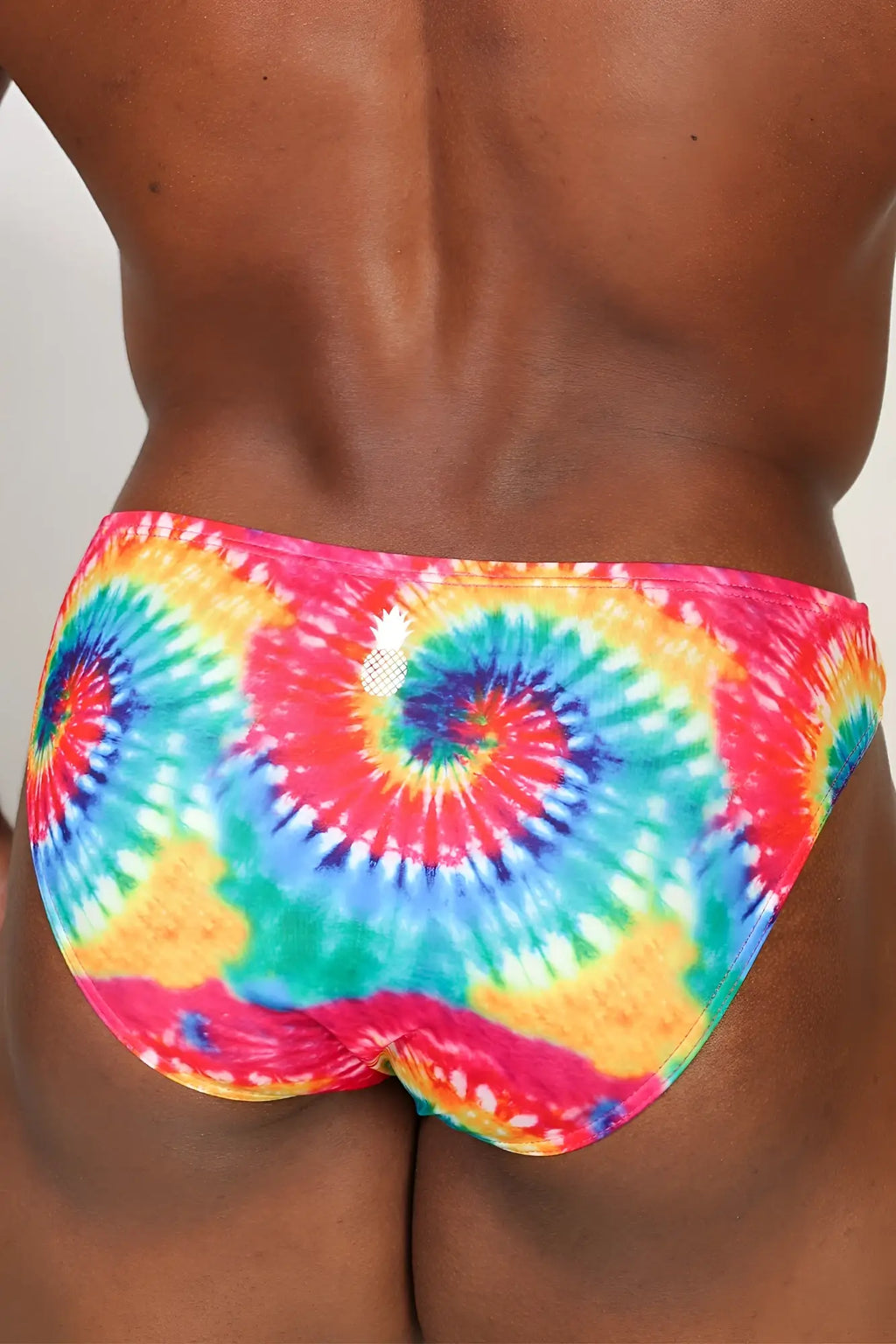 Men’s slimmer bulge briefs with vibrant rainbow tie dye swirling patterns of pink red blue green and yellow