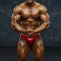 A muscular man wearing shiny red MetroMaleWear MetroMuscleWear basic competition briefs for bodybuilding use