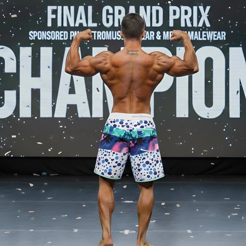 A man wearing MetroMaleWear MetroMuscleWear bubble physique board shorts with colorful abstract patterns on white