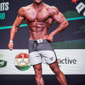 Gray and white MetroMaleWear Cordoba physique board shorts with black drawstring and shield logo on left leg