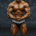 A muscular male bodybuilder wearing black and silver MetroMaleWear MetroMuscleWear DIY competition briefs