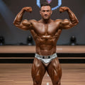 A muscular man wearing shiny silver metro musclwear elia muscle trunk briefs with black belt and decorative buckle