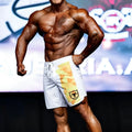 White athletic shorts with yellow and orange geometric side pattern and black msw logo by Metromalewear for physique use