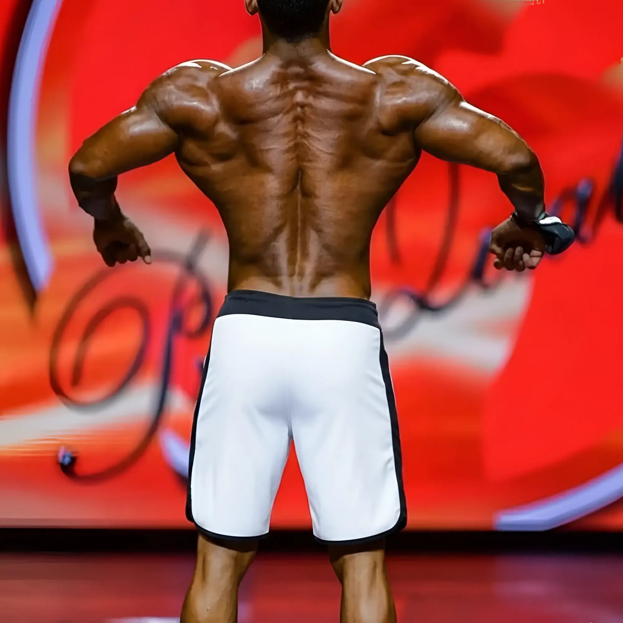 Back view of metro musclwear ifbb pro men’s physique board short in white with black trim showcasing muscular back