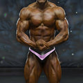 A muscular bodybuilder wearing black and purple MetroMaleWear MetroMuscleWear Mark competition briefs for bodybuilding