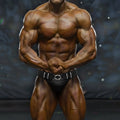 A muscular bodybuilder wearing black MetroMaleWear MetroMuscleWear muscle trunk with silver white decorative belt