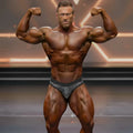 A muscular bodybuilder wearing black and silver patterned MetroMaleWear MetroMuscleWear Premier competition briefs