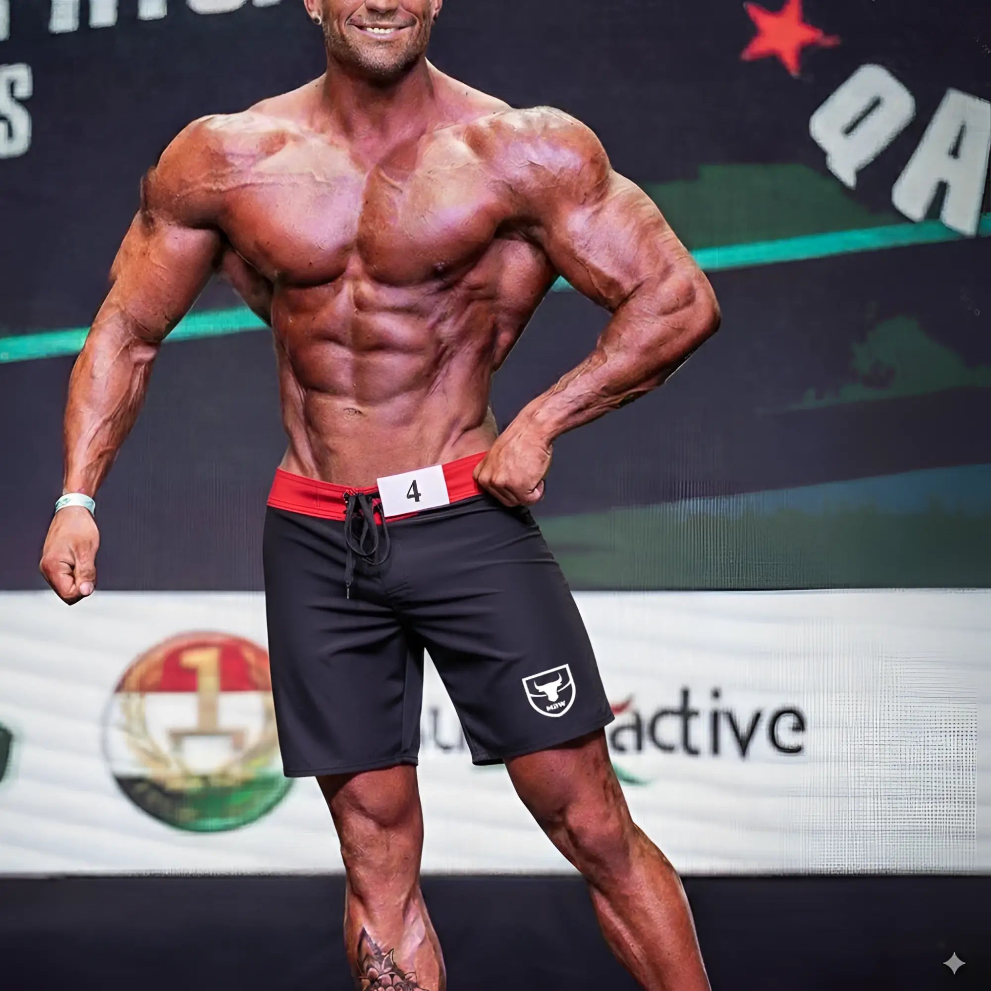 Black athletic MetroMaleWear physique board shorts with red waistband and white logo on left leg designed for performance