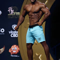 Light blue MetroMaleWear Physique board short with black waistband and small shield logo on left leg for athletic use