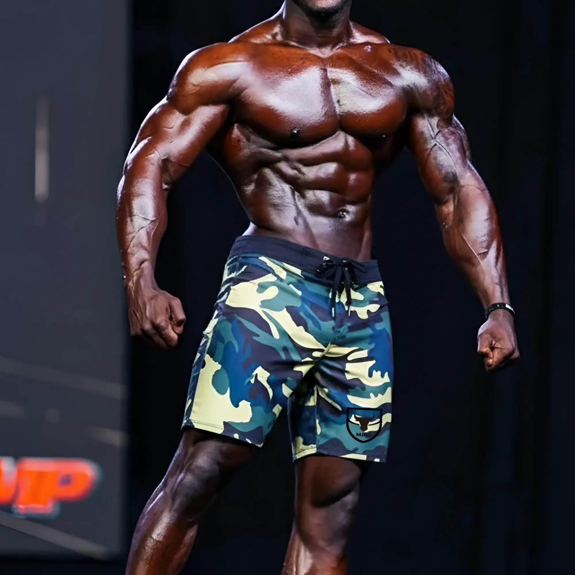 Men’s MetroMaleWear Physique board short yellow camo with black drawstring waistband and logo patch on lower left leg