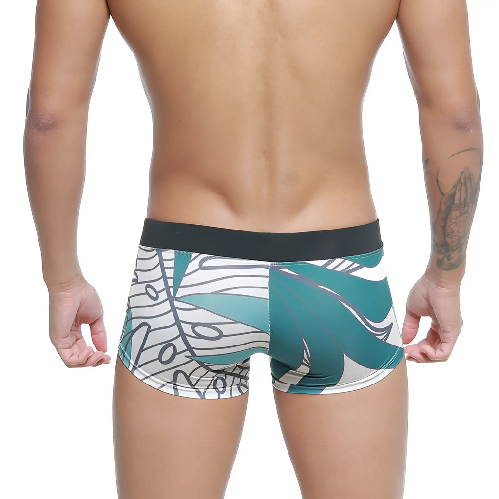 Teal and white tropical leaf patterned men’s swim boxer briefs with black elastic waistband from MetroMaleWear Profundo