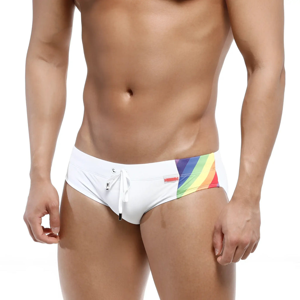 White swim trunks by metromalewear with vibrant rainbow stripe and small red brand tag for swimwear use