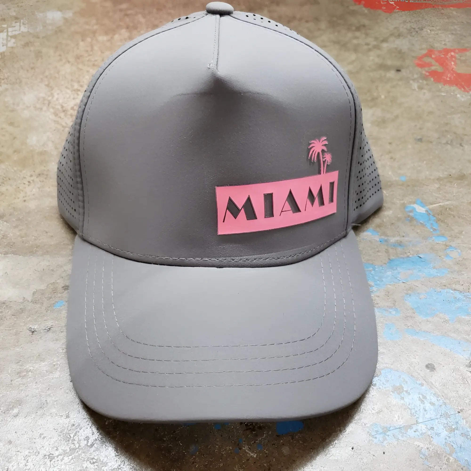 Gray miami baseball cap with pink patch featuring black lettering and two palm trees above the word miami