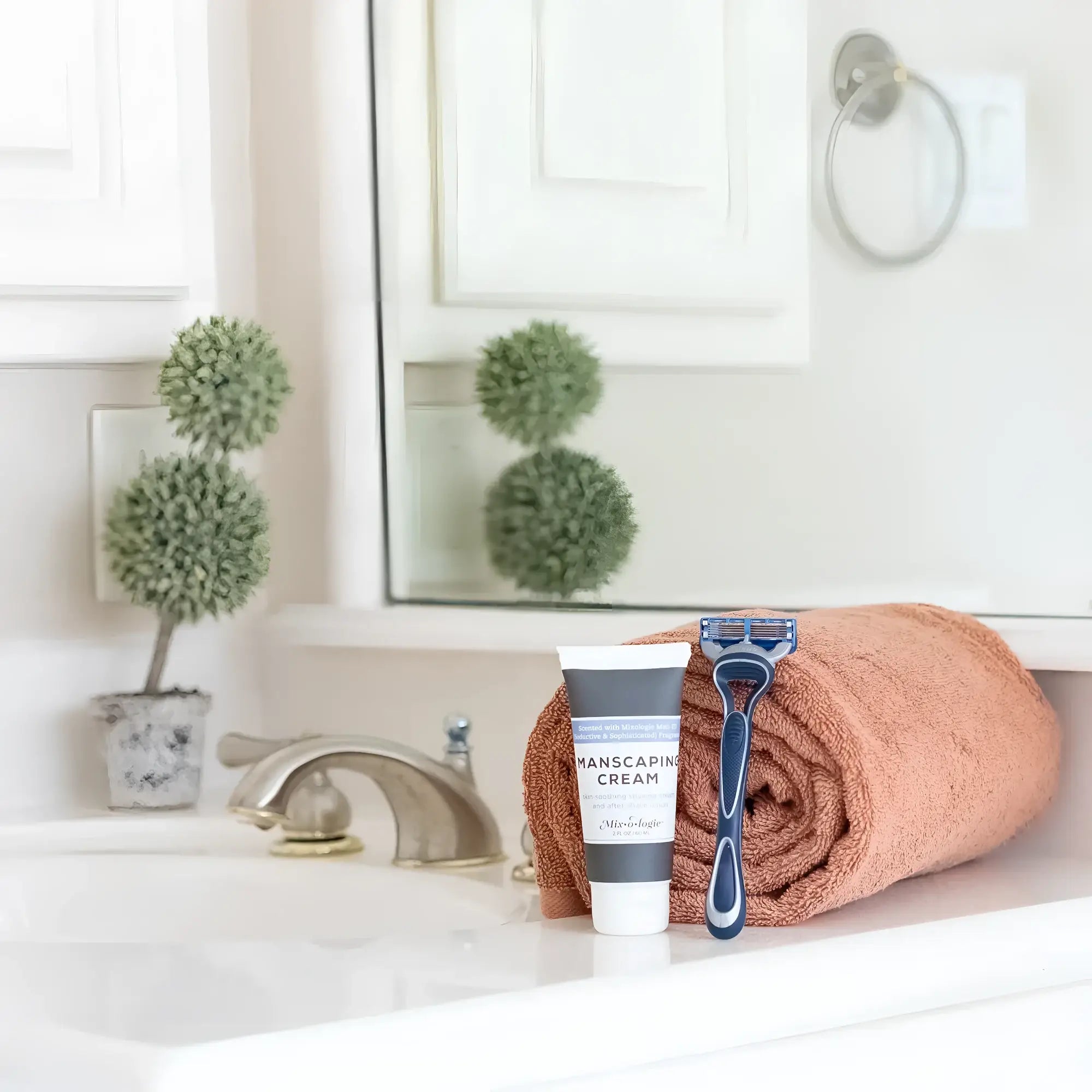 Blue and black five-blade disposable razor resting on a terracotta towel with mixologie manscaping cream shave lotion sent iii