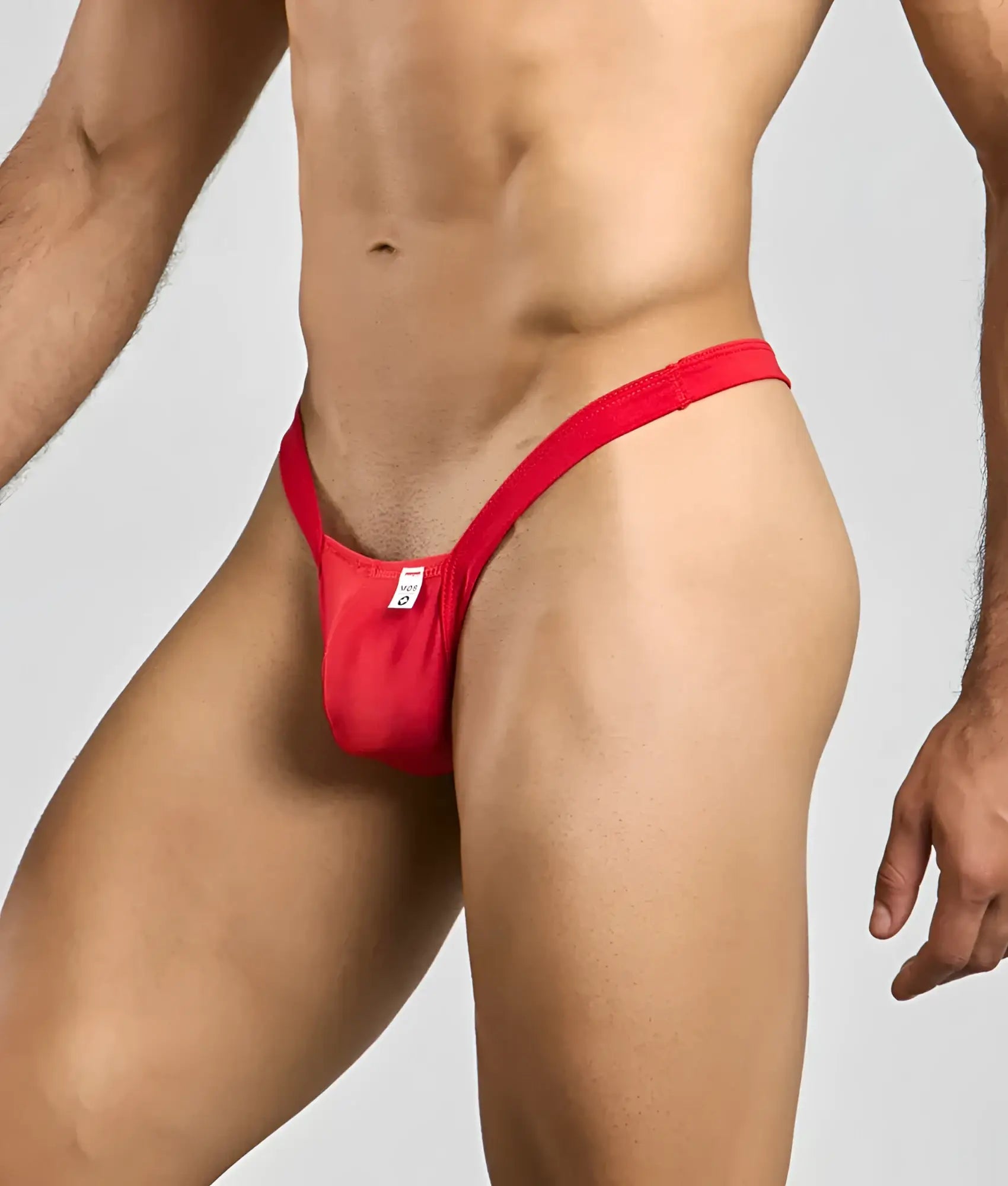 Red form-fitting mob y buns thong made of smooth fabric shown from the back with a small white tag
