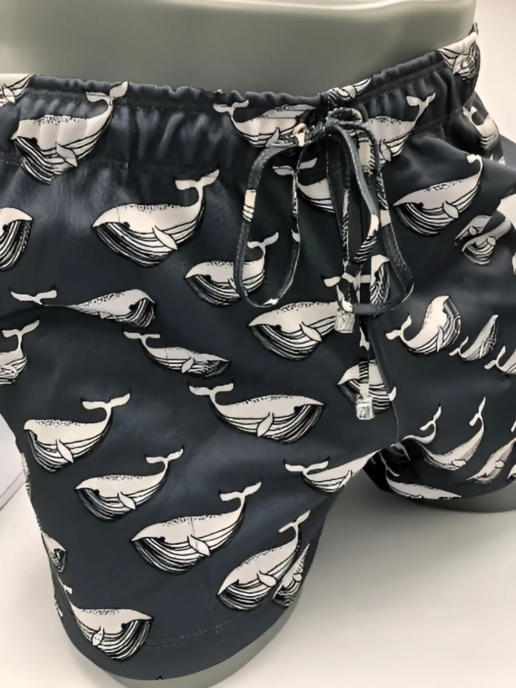Black swim trunks with a repeating white whale line art pattern called Moby Dick shorts for casual beachwear