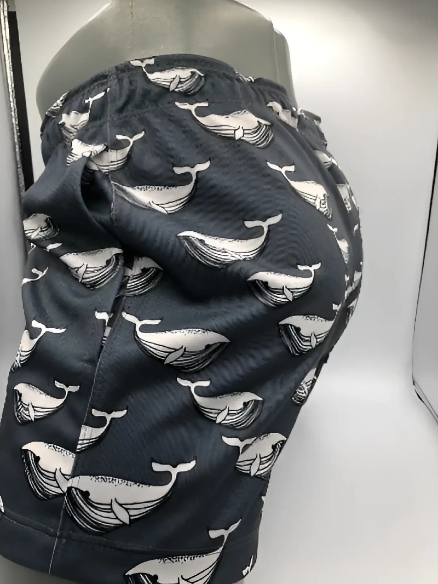 Dark gray swim trunks with a repeating white whale pattern called moby dick shorts for beachwear